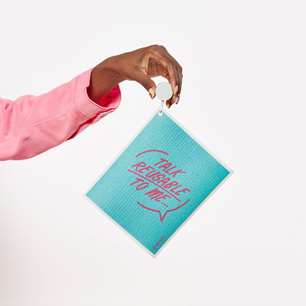 Model holding a reusable paper towel on a hook that says talk reusable to me in bright blue and pink