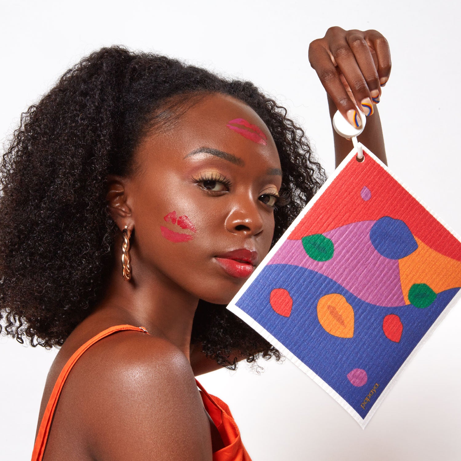 Model holding reusable paper towel with bright lips design and lipstick kisses on her face