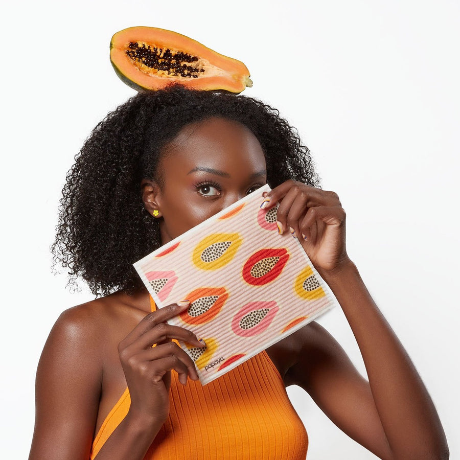 Model holding reusable paper towel with pink yellow and orange papayas design and a papaya on her head