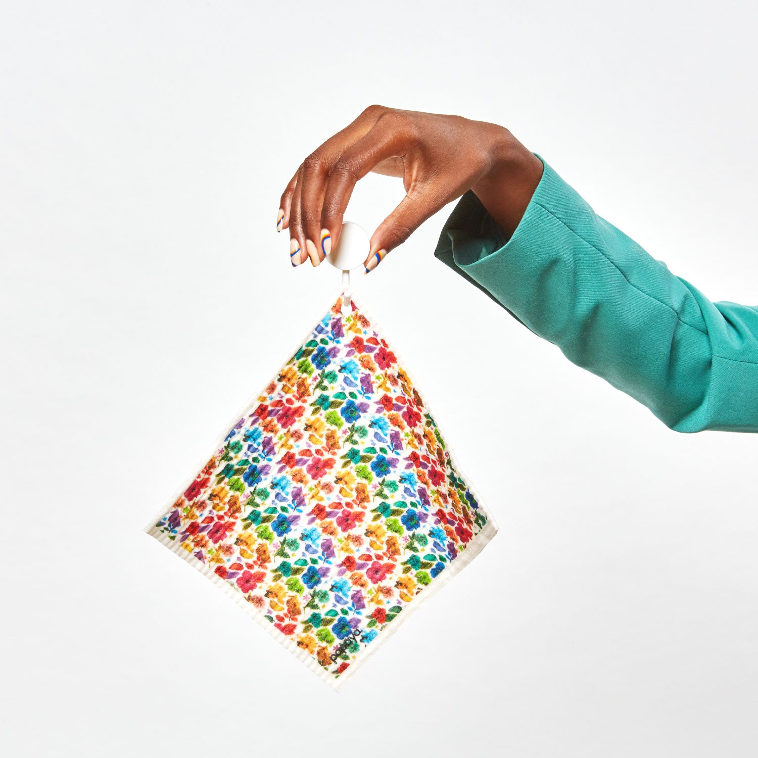 Model holding reusable paper towel hanging on a hook with colorful floral design by artist Ramzy Masri