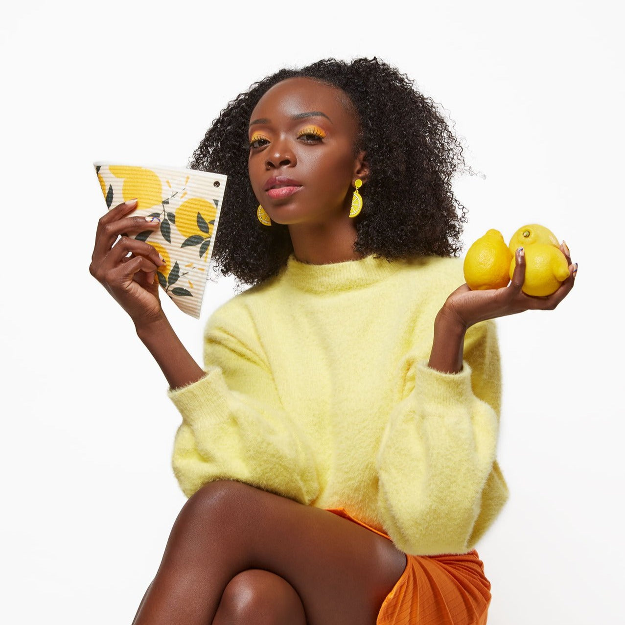 Model holding reusable paper towel with lemon design in one hand and three lemons in the other