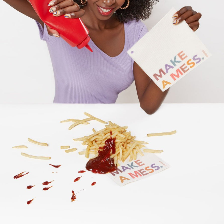 Reusable paper towel that says Make A Mess on a table covered in french fries and ketchup